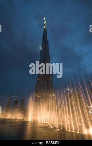 Dubai Fountains illuminated in the evening with the world's tallest skyscraper Burj Khalifa at Dubai Mall in UAE Stock Photo