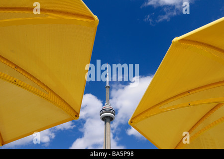 Toronto CN tower between two yellow beach umbrellas at urban beach of HTO Park with blue sky and clouds Stock Photo