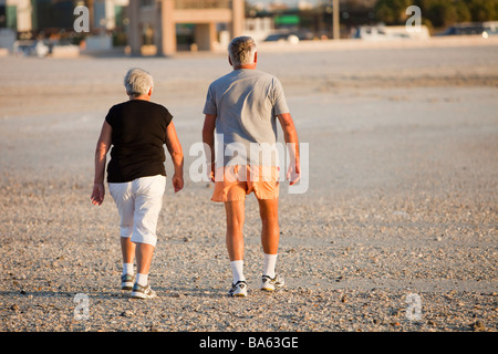 An overweight elderly couple taking exercise on a public beach in Dubai UEA Stock Photo