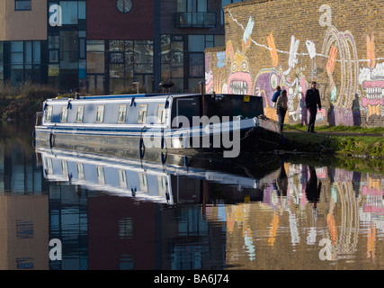 Digital still camera. A house boat, people passing, graffiti and reflection, River Lee, London. Stock Photo