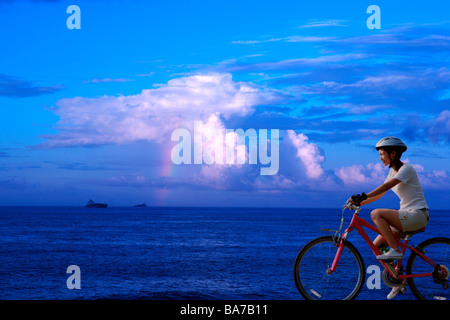 Young woman riding bicycle by sea Stock Photo