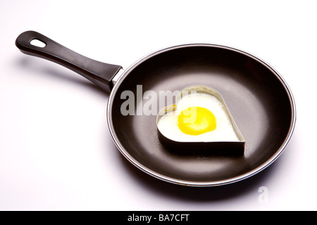 Heart shaped fried egg on pan Stock Photo