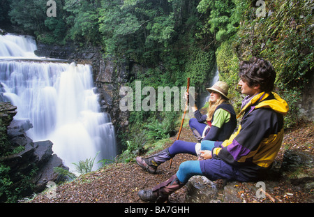 Two hikers having a rest at a waterfall, The D'Alton Falls in Cradle Mountain Lake St. Clair National Park can be reached via a Stock Photo