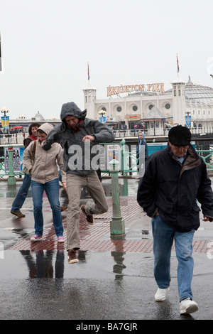 Man jumping over puddle of rain water in road, Palace Pier, Brighton Stock Photo