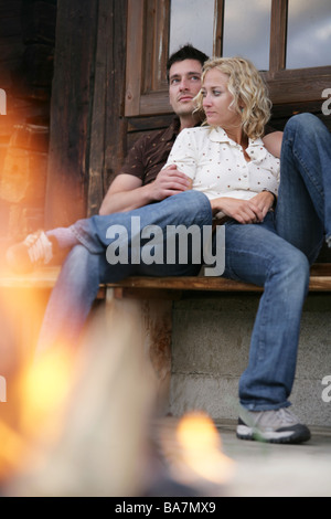 Young couple sitting on a bench near campfire, Heiligenblut, Hohe Tauern National Park, Carinthia, Austria Stock Photo