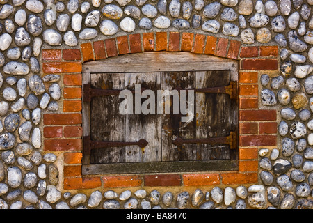 Shuttered window in brick and flint wall Stock Photo