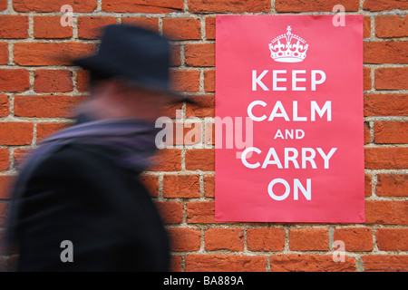 Man walking past a Second World War poster urging people to keep calm and carry on. Stock Photo