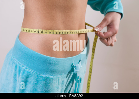 Young woman measuring waist with tape measure Stock Photo