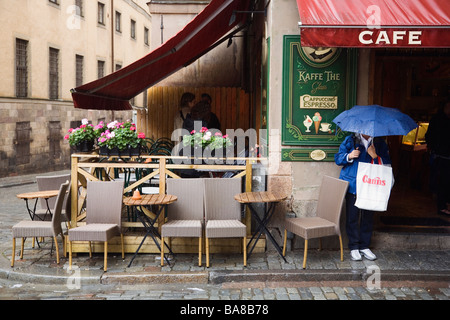 STOCKHOLM SWEDEN Jarntorget square in Gamla Stan Old Town Woman shelters from rain beneath cafe awning Stock Photo