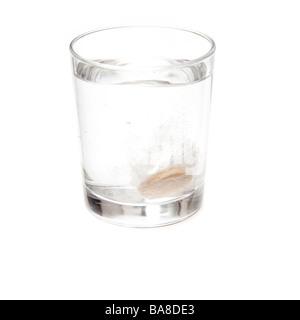 Effervescent vitamin C tablet dissolving in a glass of water. Isolated on a white studio background. Stock Photo