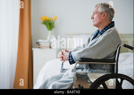 Senior man in wheelchair looking out window Stock Photo