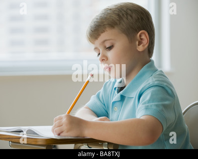 Boy writing in classroom Stock Photo