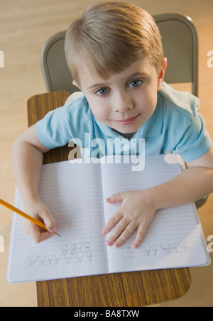 Boy writing letters in classroom Stock Photo