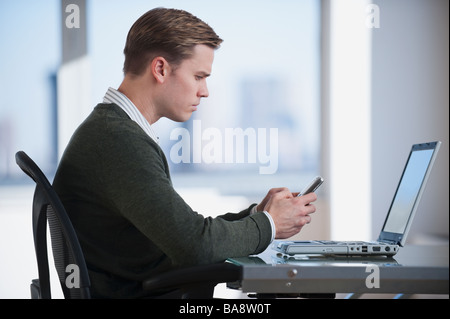 Businessman text messaging in office Stock Photo