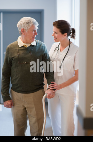 Nurse helping senior man with cane Stock Photo