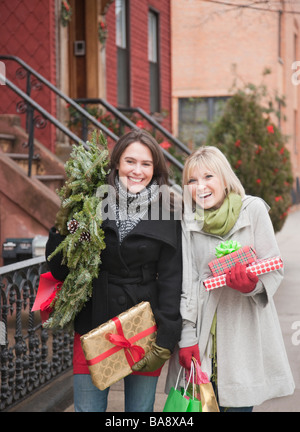 Women carrying Christmas gifts on urban street Stock Photo