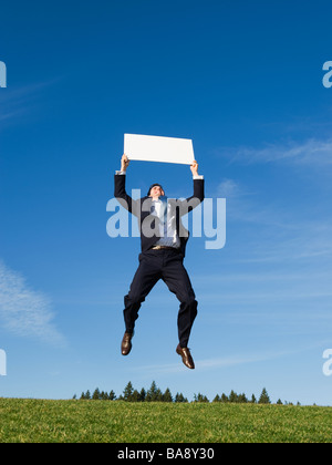 Businessman jumping with blank sign Stock Photo