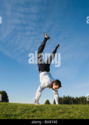 Businessman doing handstand outdoors Stock Photo