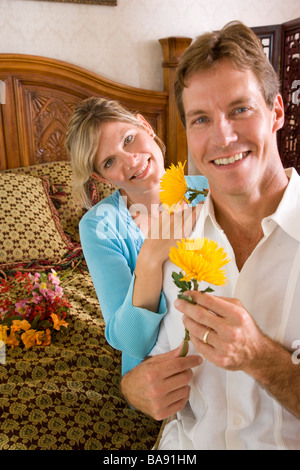 Portrait of happy couple on bed with flowers, close up Stock Photo