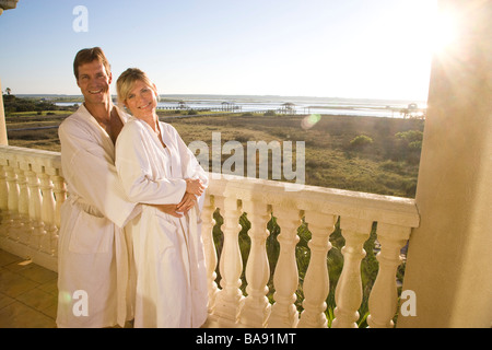 Portrait of happy couple standing on balcony in bathrobes Stock Photo