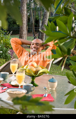 African-American man sitting at breakfast table in garden Stock Photo