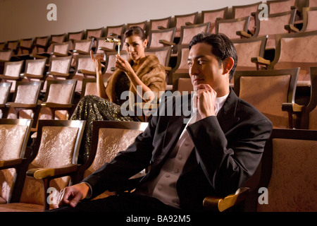 Hispanic woman in formal gown and man tuxedo sitting in theater Stock Photo