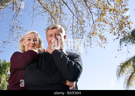 Portrait of senior couple standing under tree in garden, close up Stock Photo