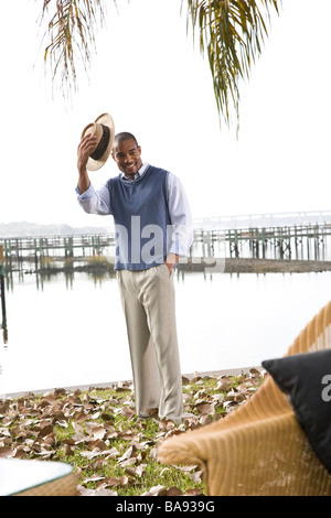 African American gentleman tipping hat near water at garden party Stock Photo