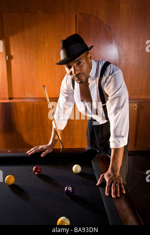 African American man leaning over billiards table in 1920s bar Stock Photo