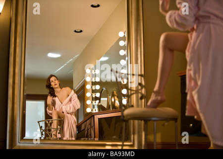 Woman in pink bathrobe standing in bathroom stroking leg Stock Photo