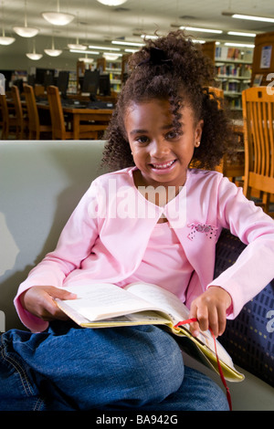 African American school girl sitting in library armchair Stock Photo