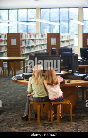 Two elementary school girls using computer in library, rear view Stock Photo
