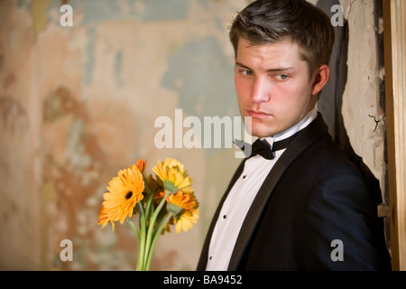 Portrait of young man in tuxedo holding flowers Stock Photo