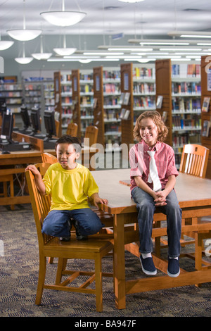 Asian and Caucasian elementary school boys sitting in library Stock Photo