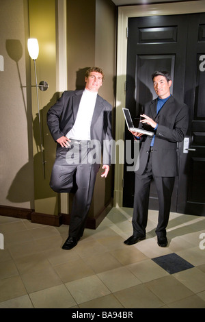 Multi-racial businessmen conversing in hallway Stock Photo