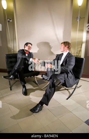 Multi-racial businessmen shaking hands in modern office lobby Stock Photo