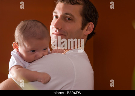 Close-up portrait of father holding 3 month old baby over his shoulder Stock Photo