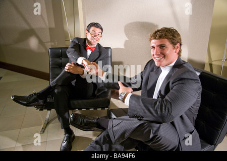Multi-racial businessmen shaking hands in modern office lobby Stock Photo