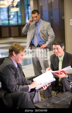 Businessmen working in modern office lobby Stock Photo