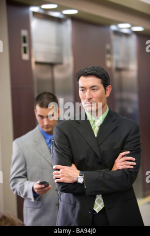 Multi-racial businessmen waiting for elevator in modern office lobby Stock Photo