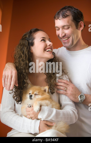 Young happy couple holding Pomeranian dog Stock Photo