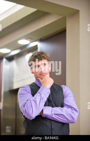 Serious businessman thinking and waiting for elevator in office lobby Stock Photo