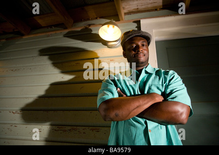Portrait of African American man standing on porch of house at night Stock Photo