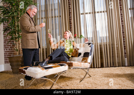 Romantic middle-aged couple with drinks in living room Stock Photo