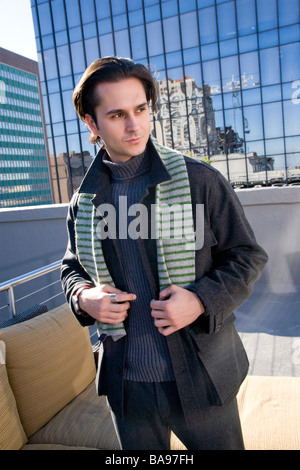 Young man in winter clothing standing on rooftop of downtown condo in city Stock Photo