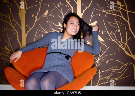 Young Asian woman sitting and relaxing in modern chair Stock Photo