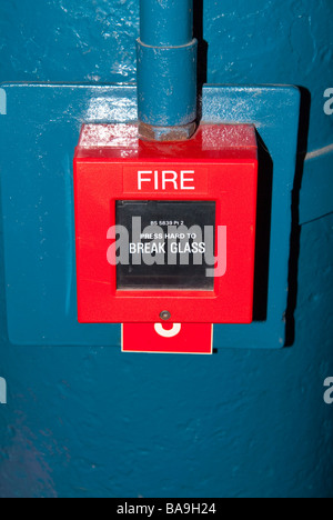 A fire alarm box with instructions to break the glass and press Stock