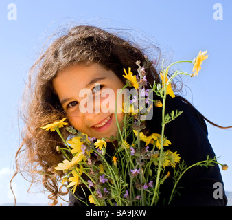 little girl smiling holding wild flowers Stock Photo