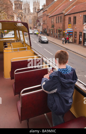 A young boy on the open top deck of a sightseeing bus travelling through the city of York,Yorkshire,Uk Stock Photo