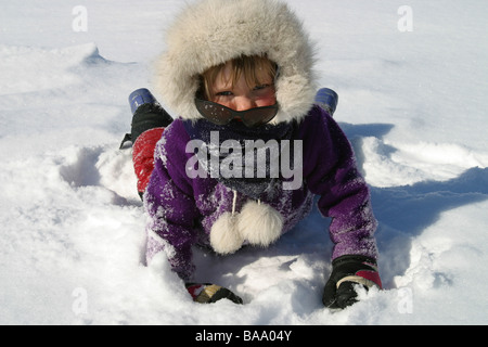 A young blond-haired girl in a fur rimmed hood and jacket in the snow in the Arctic community of Old Crow, Yukon Territory. Stock Photo